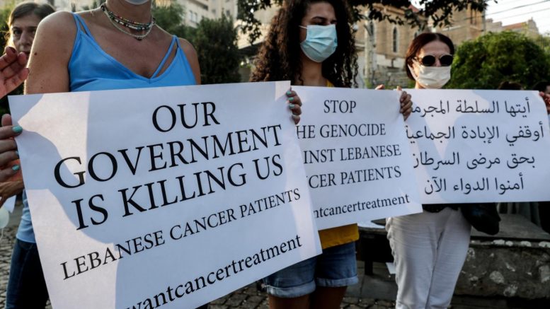 Demonstrators carry placards during a gathering by cancer patients to protest against a shortage of medicines in Beirut on August 26, 2021 (AFP)